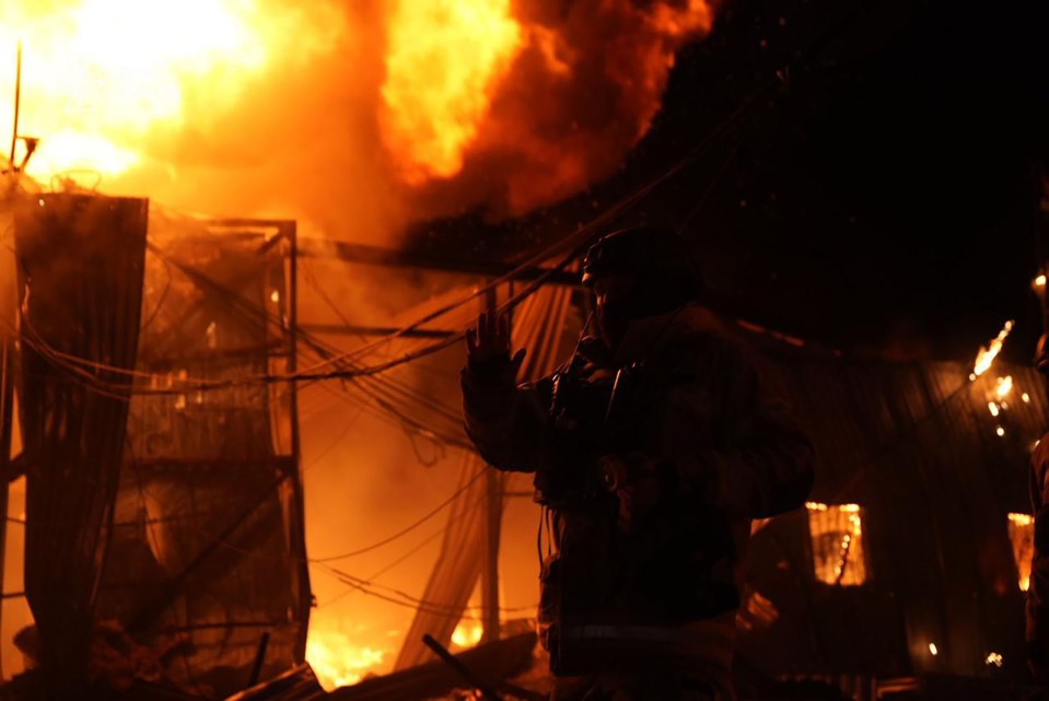 Firefighter silhouetted against a burning building.