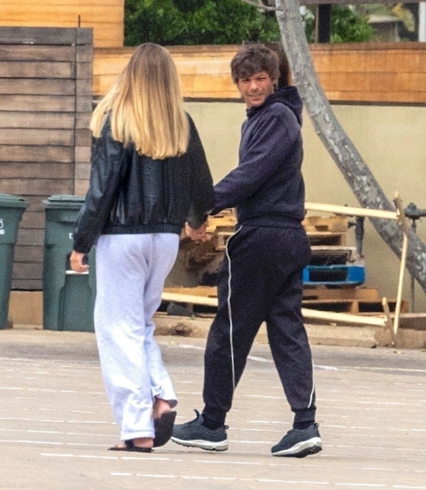 Louis Tomlinson and Zara McDermott holding hands.