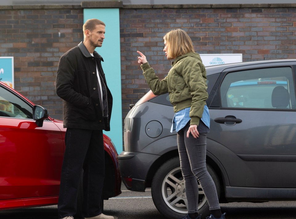 A man and woman arguing near two cars, one of which is damaged.