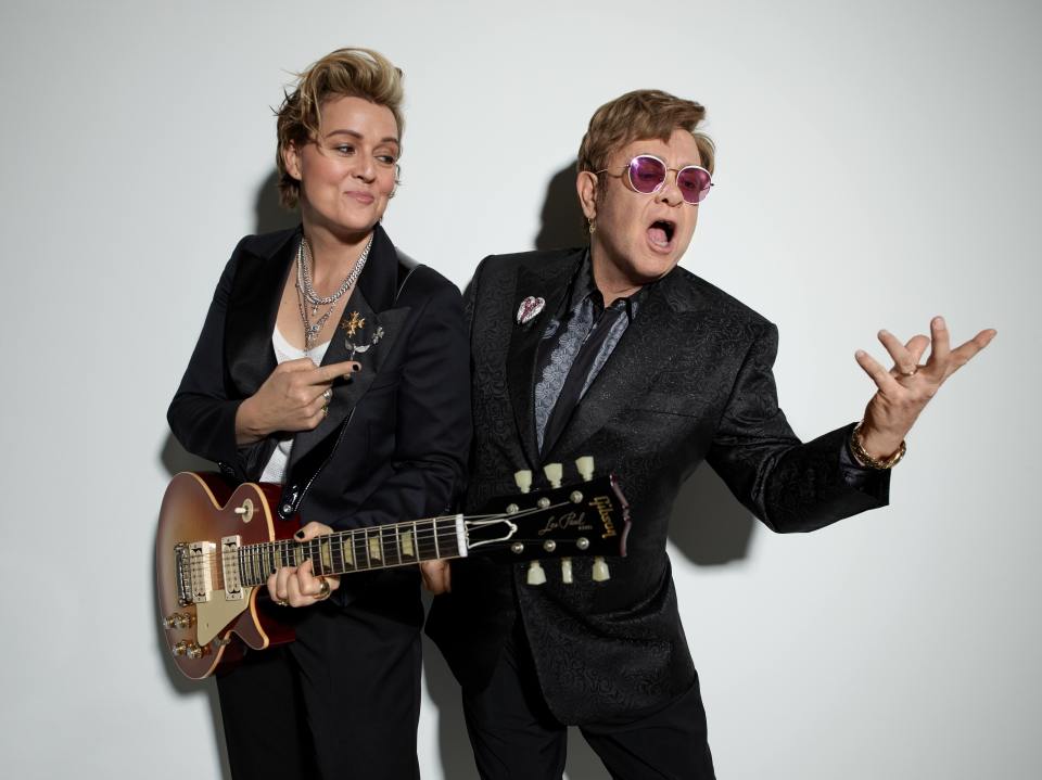 Brandi Carlile and Elton John posing together, holding guitars.