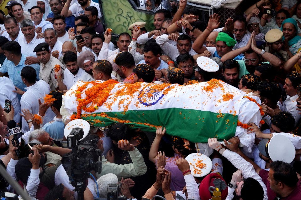 People carrying the body of a Navy officer draped in the Indian flag.