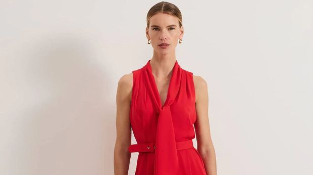 Woman in a red sleeveless dress with a tie neck.