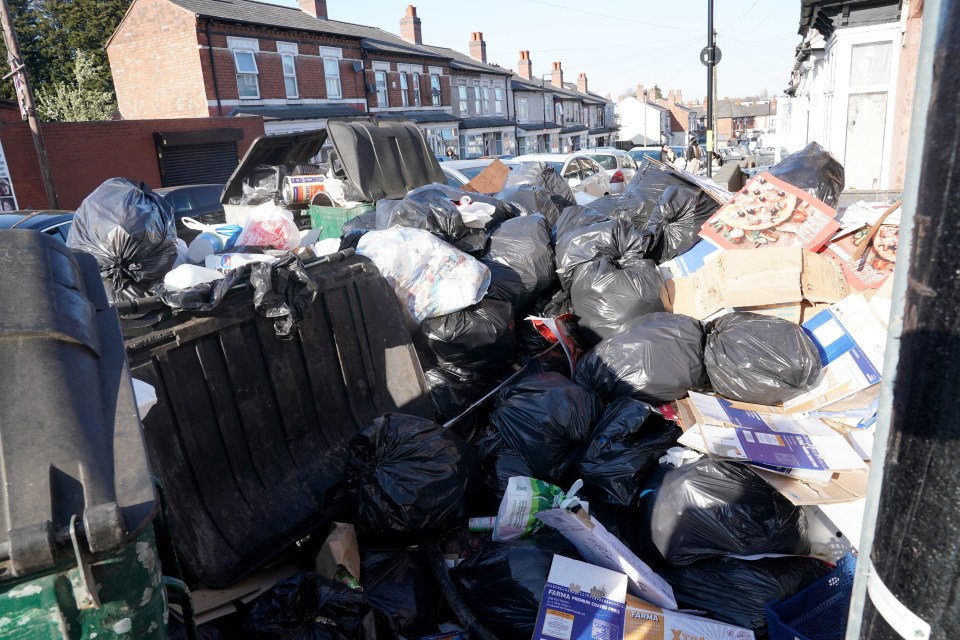Pile of garbage bags and refuse overflowing from a bin.