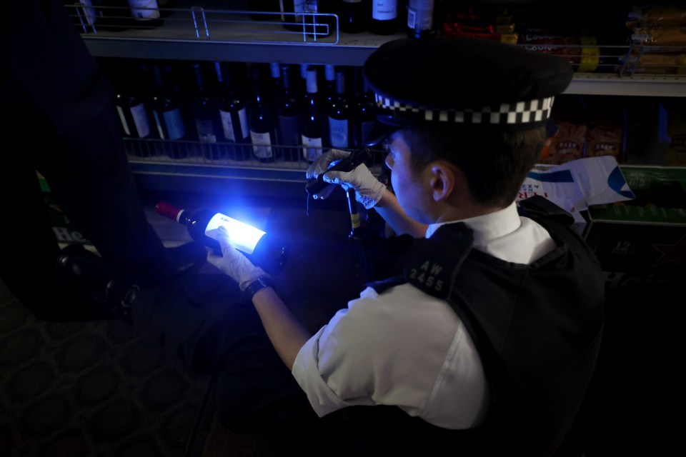 Police officer using a UV light to check for stolen goods in a shop.
