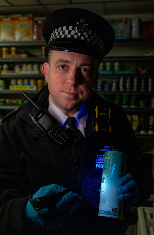 Police officer inspecting stolen goods using a UV torch.