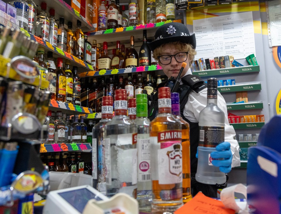 Police officer checking alcohol bottles in a shop for stolen goods.