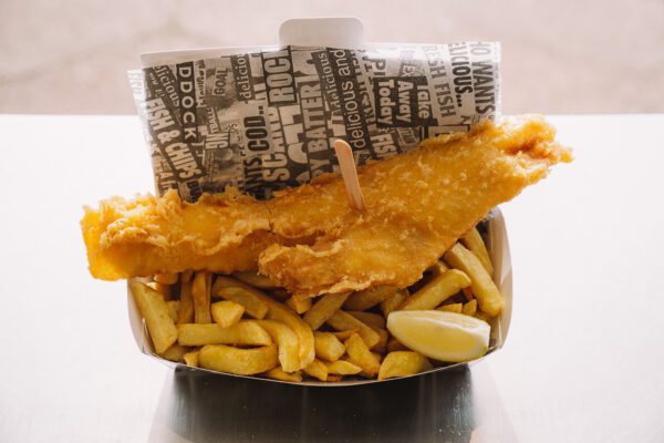 Fish and chips with lemon wedge in a container.