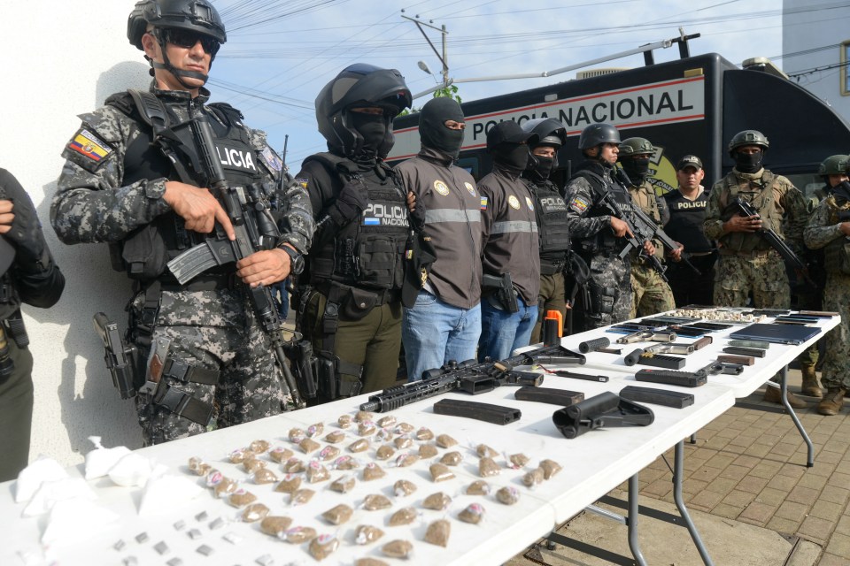 Police officers display seized drugs, weapons, and cell phones.