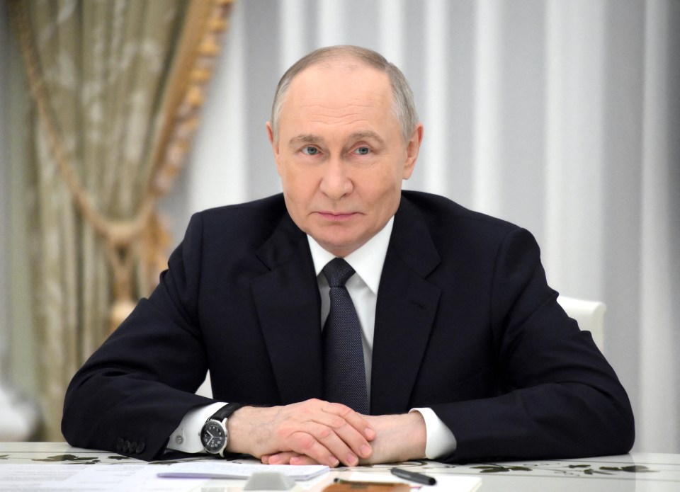 Vladimir Putin sitting at a table.