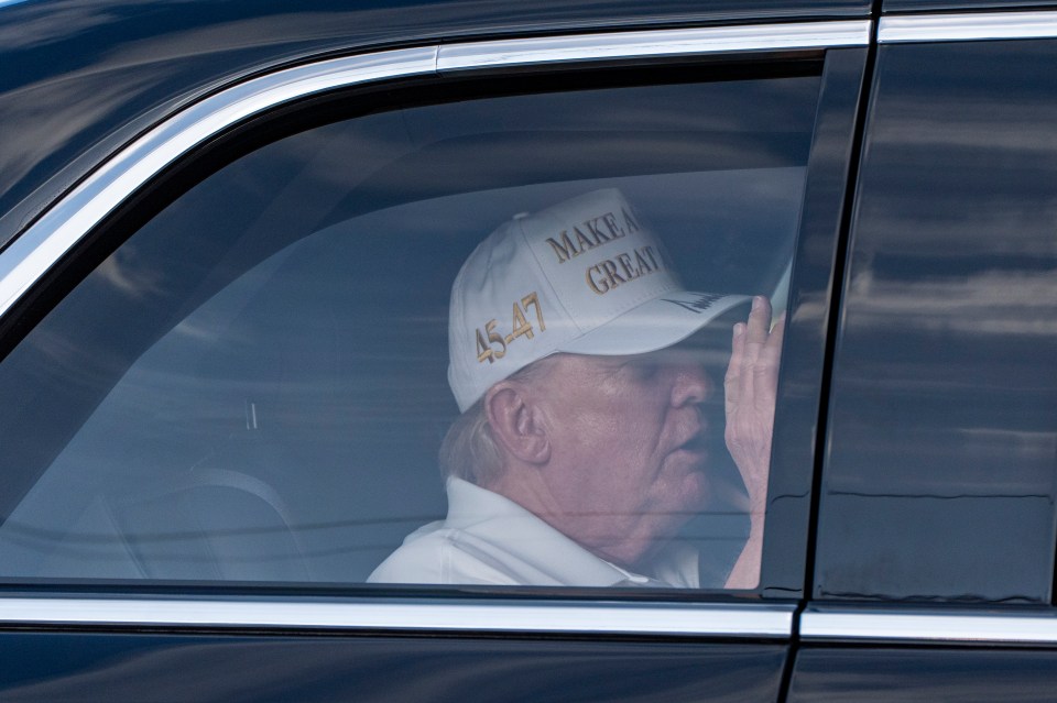 Donald Trump in a car, wearing a "Make America Great Again" hat.