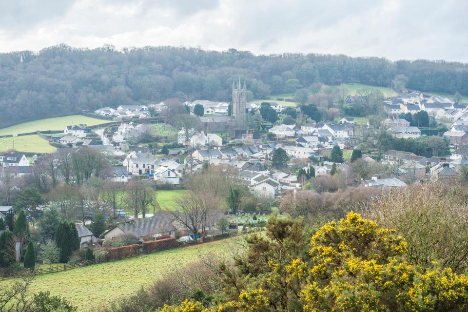 Aerial view of a village nestled in a valley, with a church steeple visible.