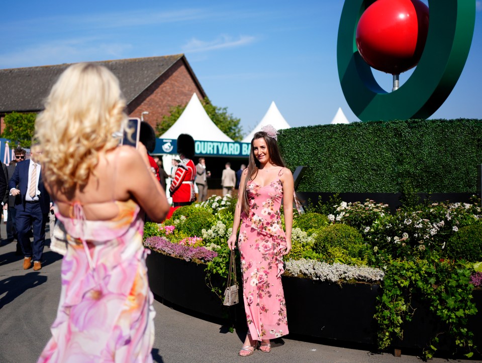 Woman in floral dress being photographed at a horse race.