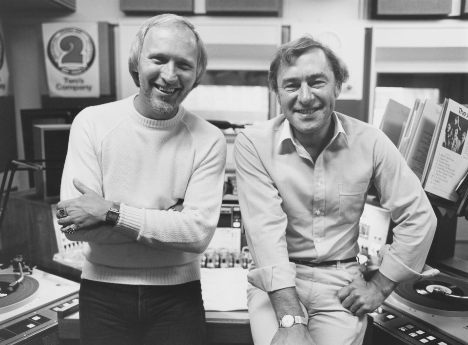 Black and white photo of Colin Berry and Ray Moore, BBC Radio disc jockeys, in a studio.