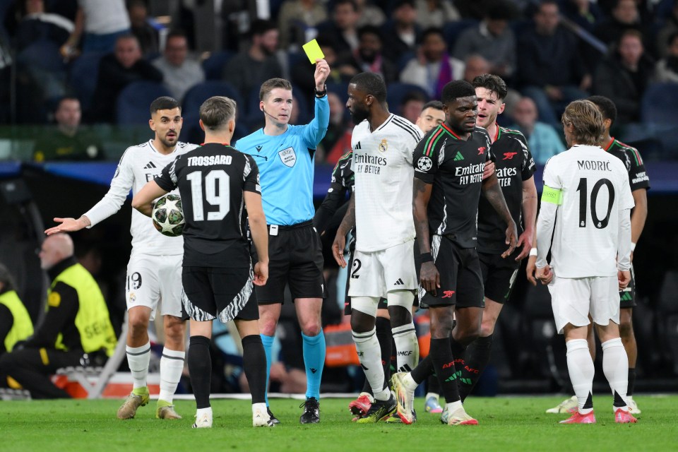Referee showing a yellow card to an Arsenal player.