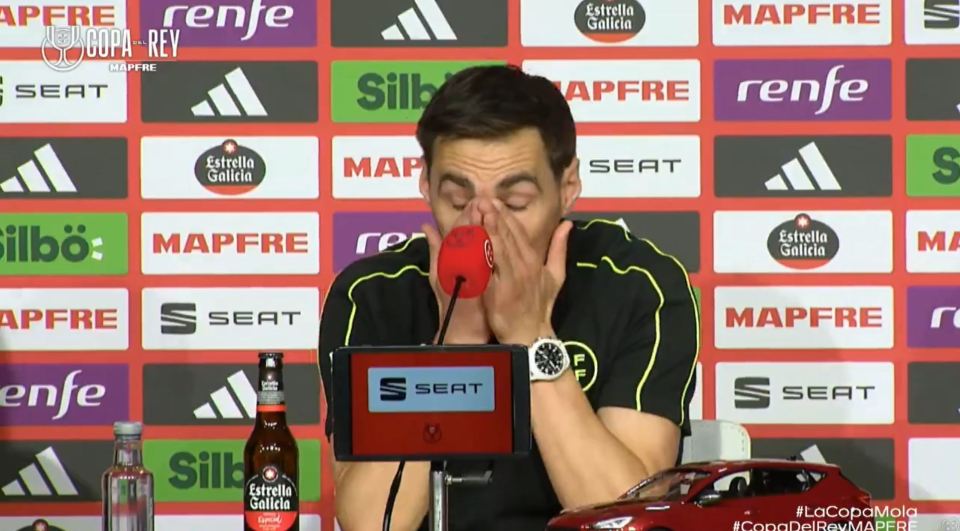 A man covering his face with his hands at a press conference.