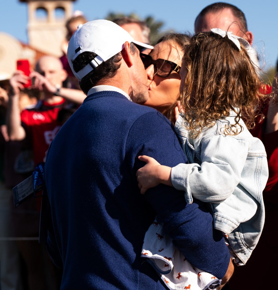 Rory McIlroy kissing his wife Erica while holding their daughter.