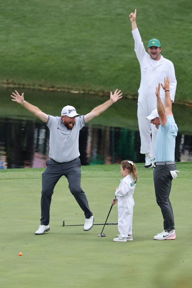 Rory McIlroy celebrates with his daughter and Shane Lowry at a golf tournament.