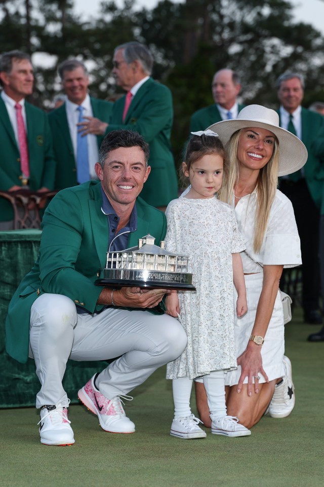 Rory McIlroy with his daughter and wife, holding the Masters trophy.