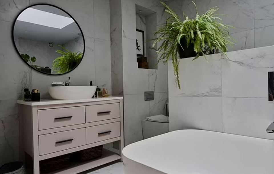 Modern bathroom with a pink vanity, a freestanding bathtub, and marble tile.