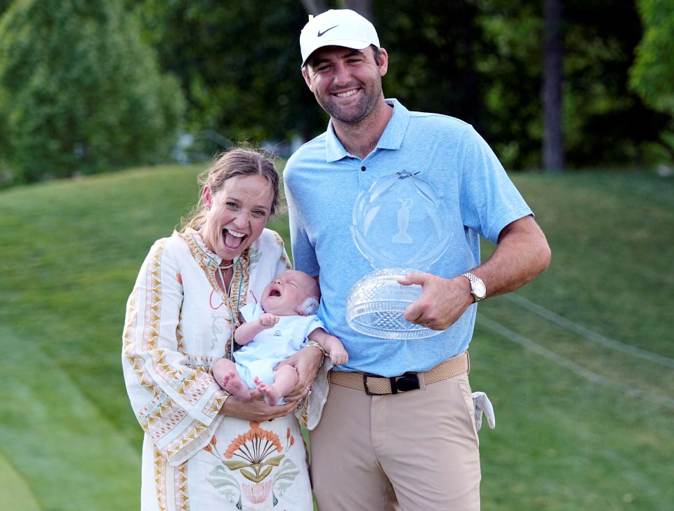 Scottie Scheffler, his wife Meredith Scudder, and their baby pose with a golf trophy.