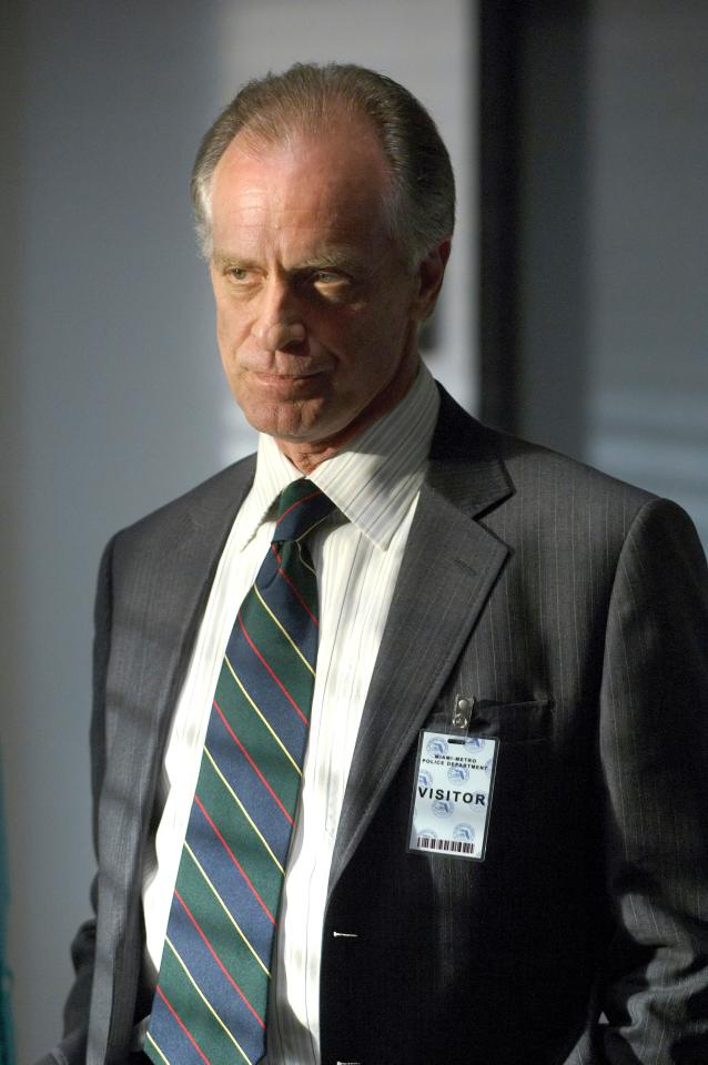Keith Carradine as Lt. Frank Lundy in a suit and tie, wearing a visitor's badge.
