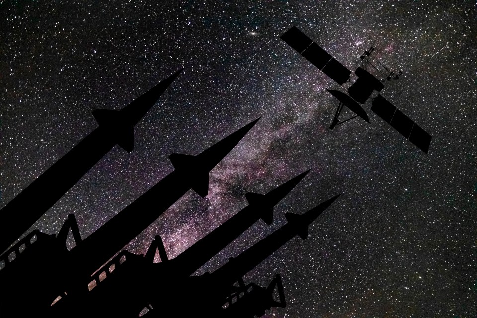 Silhouetted missiles and a satellite against a starry night sky.
