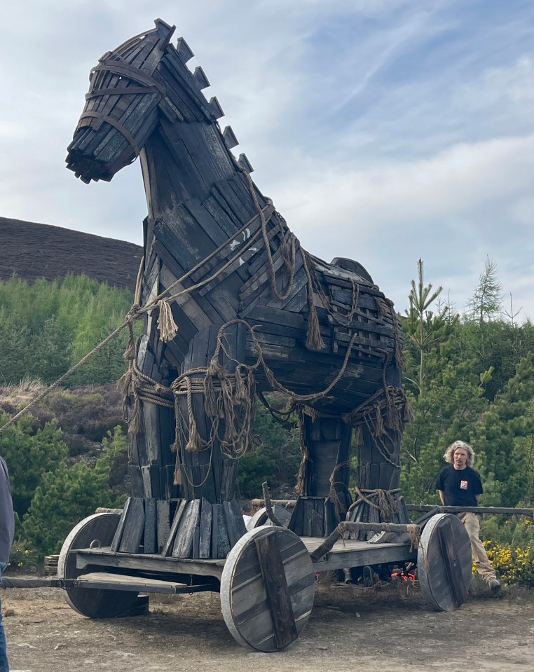 A large wooden Trojan horse on a cart, being pushed by people in the Scottish Highlands.