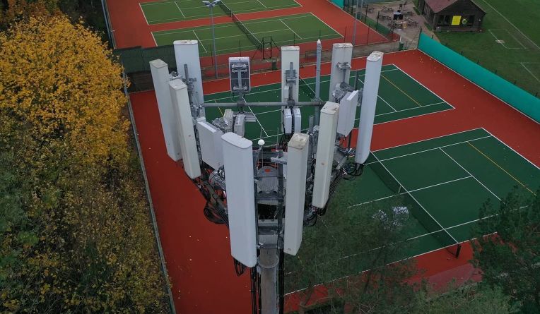 Aerial view of a cellular tower next to tennis courts.