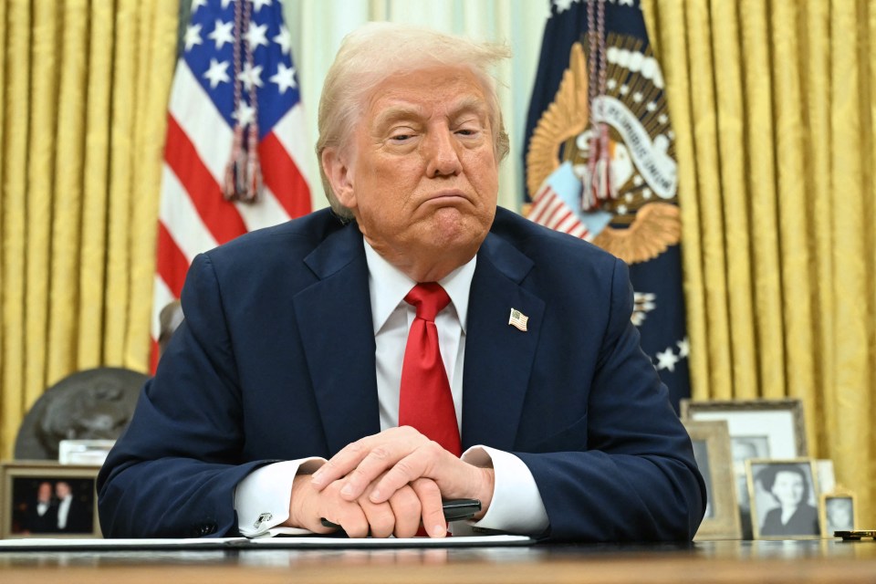 President Donald Trump seated at the Resolute Desk in the Oval Office.