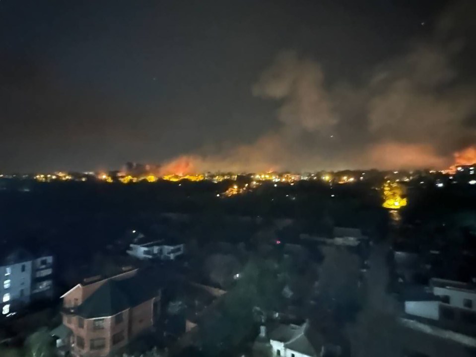 Nighttime view of fires and smoke over a city.