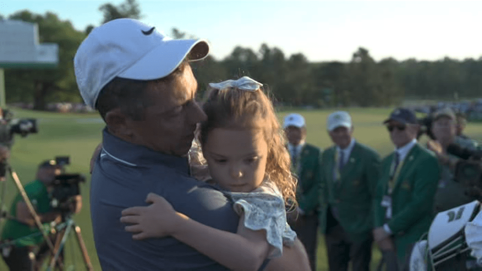 Golfer holding a young girl.