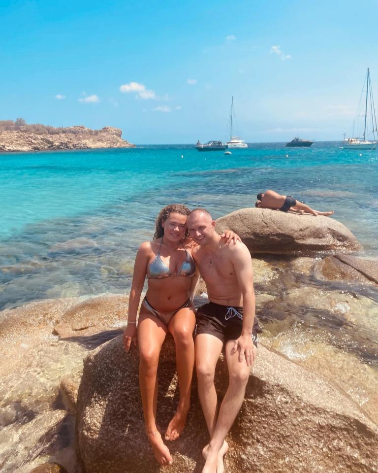 Sean Bowen and Harriett Matthews sitting on rocks at the beach.