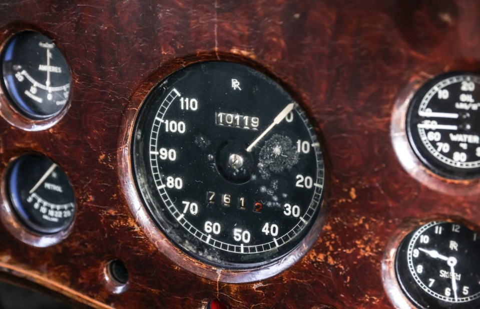 Close-up of a vintage car's dashboard, showing the speedometer and other gauges.