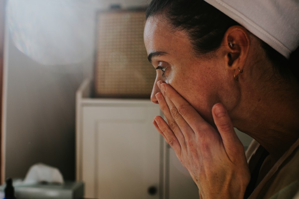 Woman applying skincare to her face.
