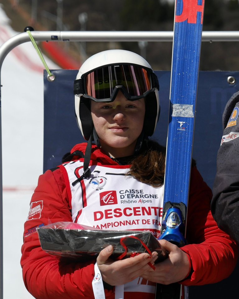 A female skier holding a prize and her skis.
