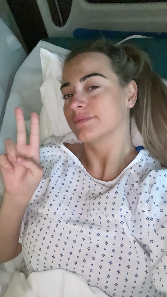 Woman in hospital gown gives peace sign.