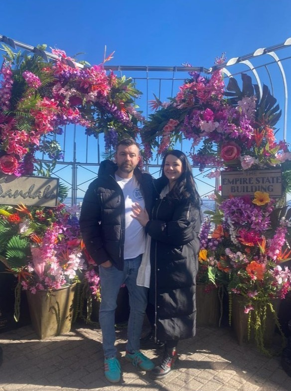 Couple posing in front of floral display at the Empire State Building.