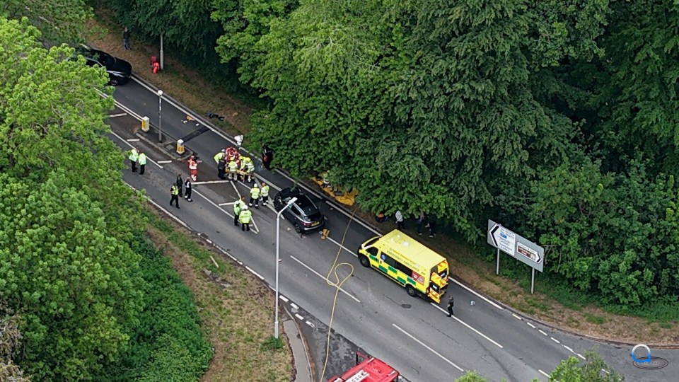 Aerial view of a road accident scene with emergency responders and damaged vehicles.