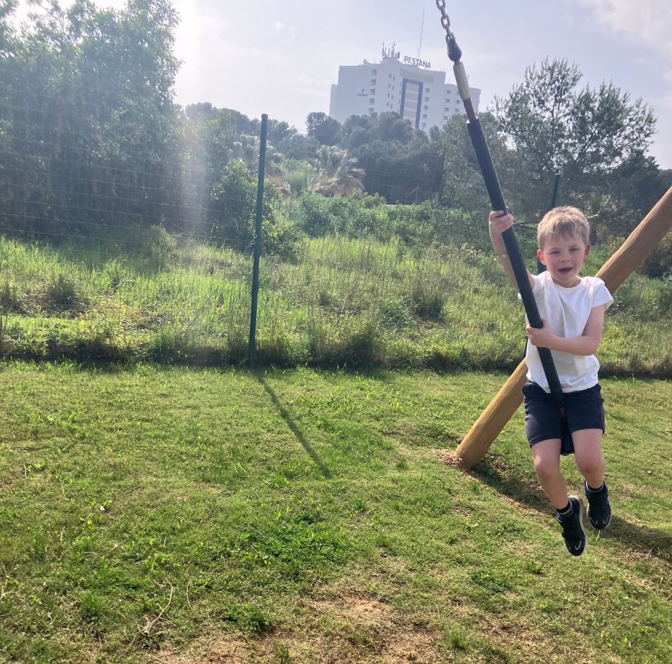 Boy swinging on a playground swing set.
