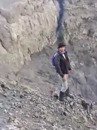 Person standing near the edge of a volcano.