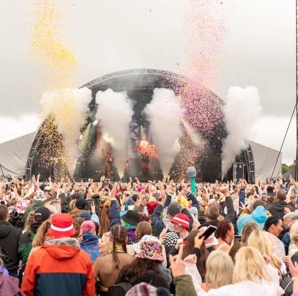 Crowd at a music festival with confetti falling.