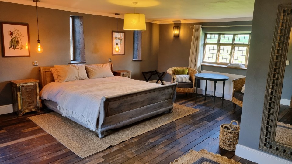 Bedroom with a large wooden bed, wooden floors, and a large window.