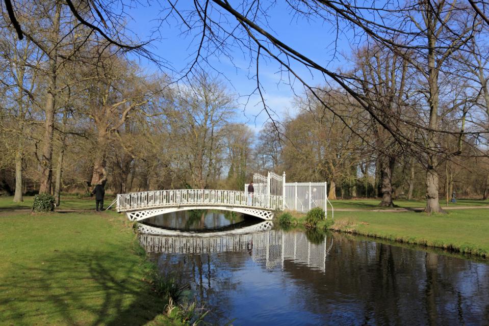 White bridge over a calm river in a park.