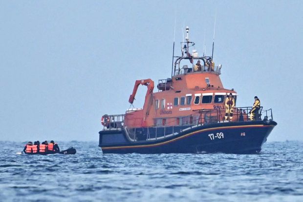 A lifeboat rescuing migrants from a small inflatable boat in the English Channel.