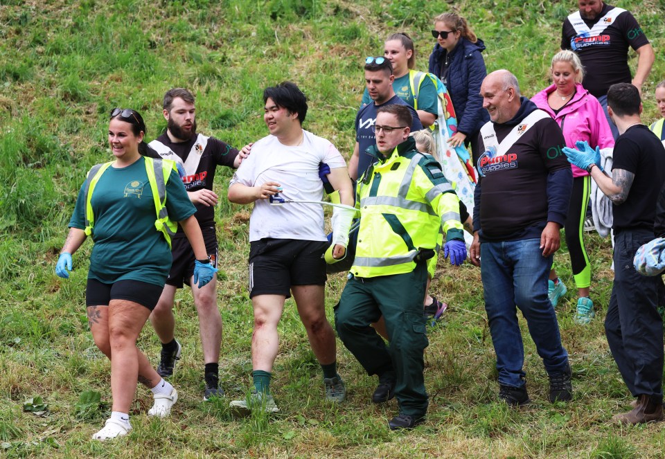 A cheese-rolling contestant being assisted by medical personnel after a race.