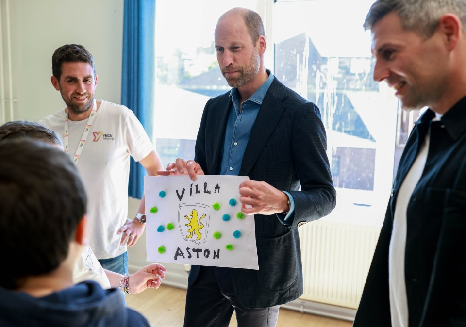 Prince William looking at a child's drawing of a crest.