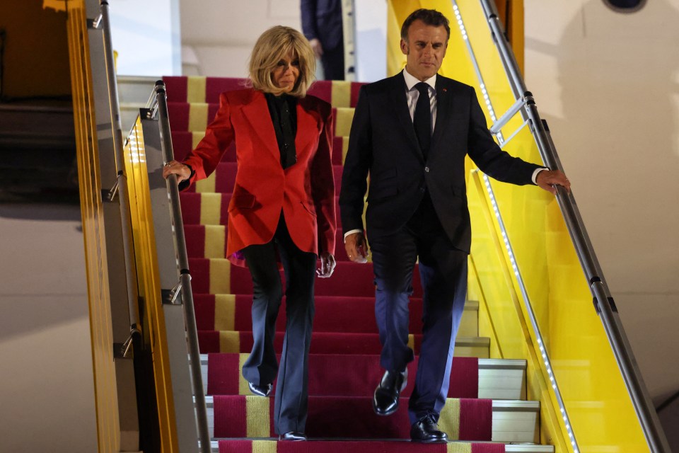 President Emmanuel Macron and his wife Brigitte Macron descending the stairs of a plane.