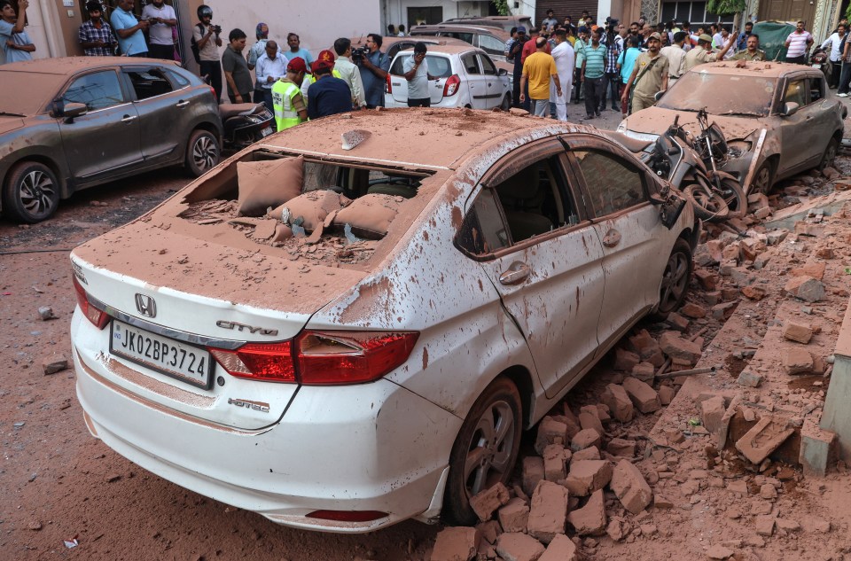Damaged cars covered in dust and debris after Pakistani artillery shelling.