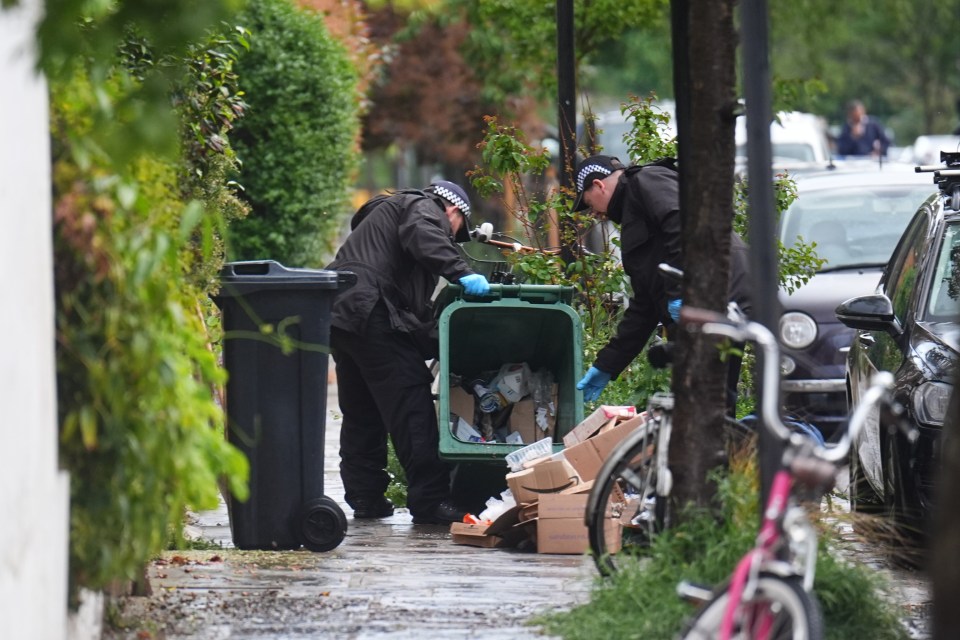 Police officers searching a bin during a fire investigation.