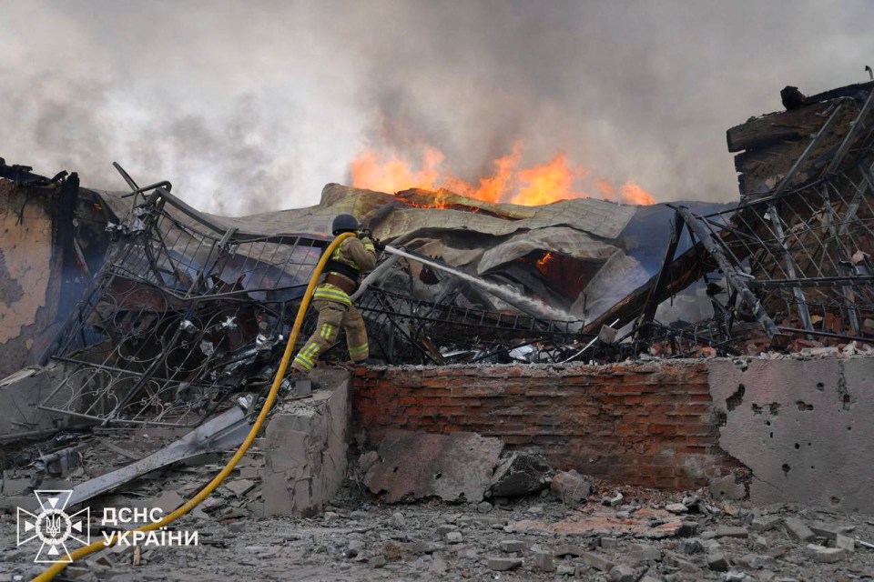 Firefighter extinguishing a fire in a damaged building.